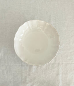 Top-down view of a white ceramic bowl on a light fabric tablecloth, photographed from above.