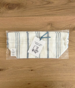 Colonial Check tissue cover in white and blue stripes, in plastic packaging on a wooden surface